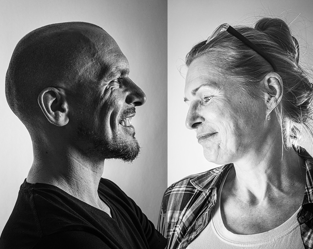 Czarno-biała fotografia przedstawiająca uśmiechnietego mężczyznę i kobietę, która patrzy w dal, można wyczytać z jej twarzy wzruszenie