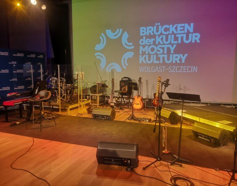 Pusta scena Studia Koncertowego S1 z instrumentami przed koncertem, w tle logo Mosty Kultury